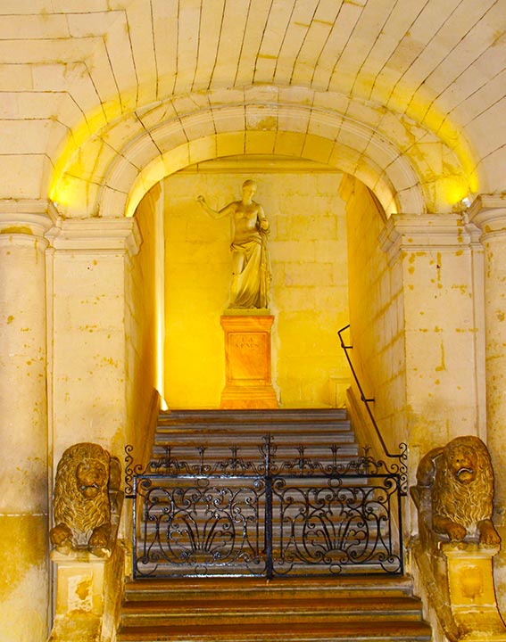 Vue sur sur des escaliers avec une statue en haut des marches.