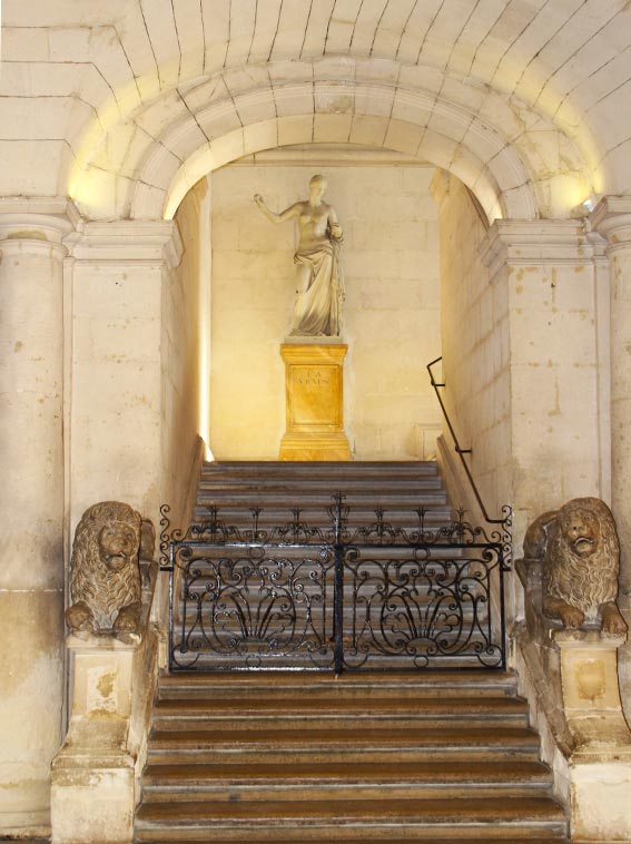 Vue sur sur des escaliers avec une statue en haut des marches.