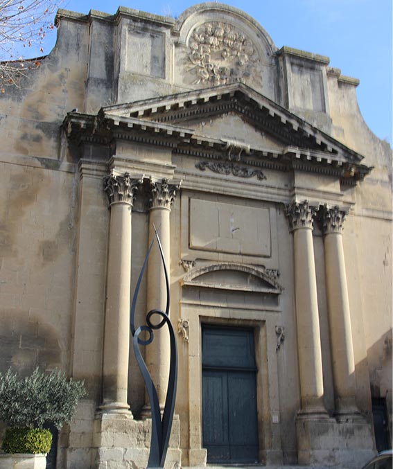 Vue sur un ancien bâtiment style romain, avec une statue devant de couleur noire.
